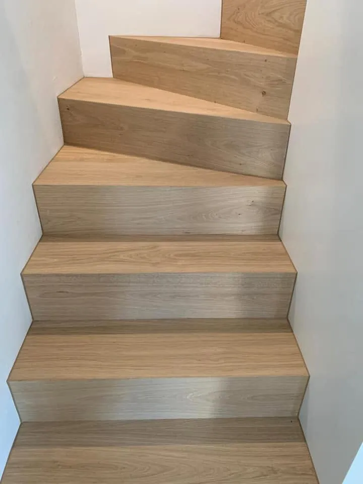 Gewendelte Treppe mit Stufen aus Eichenparkett in hellem Treppenhaus